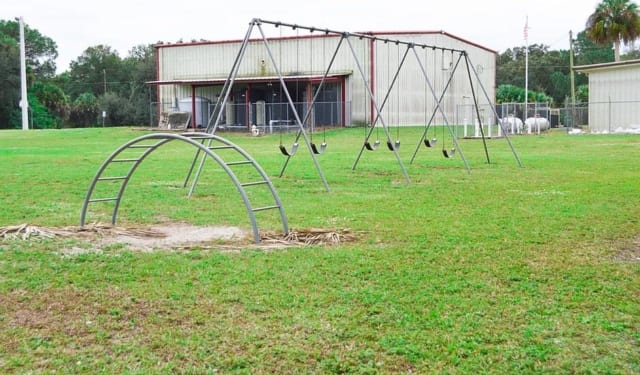 Swing set and climbing tunnel on grass at Felda Park in LaBelle, Florida